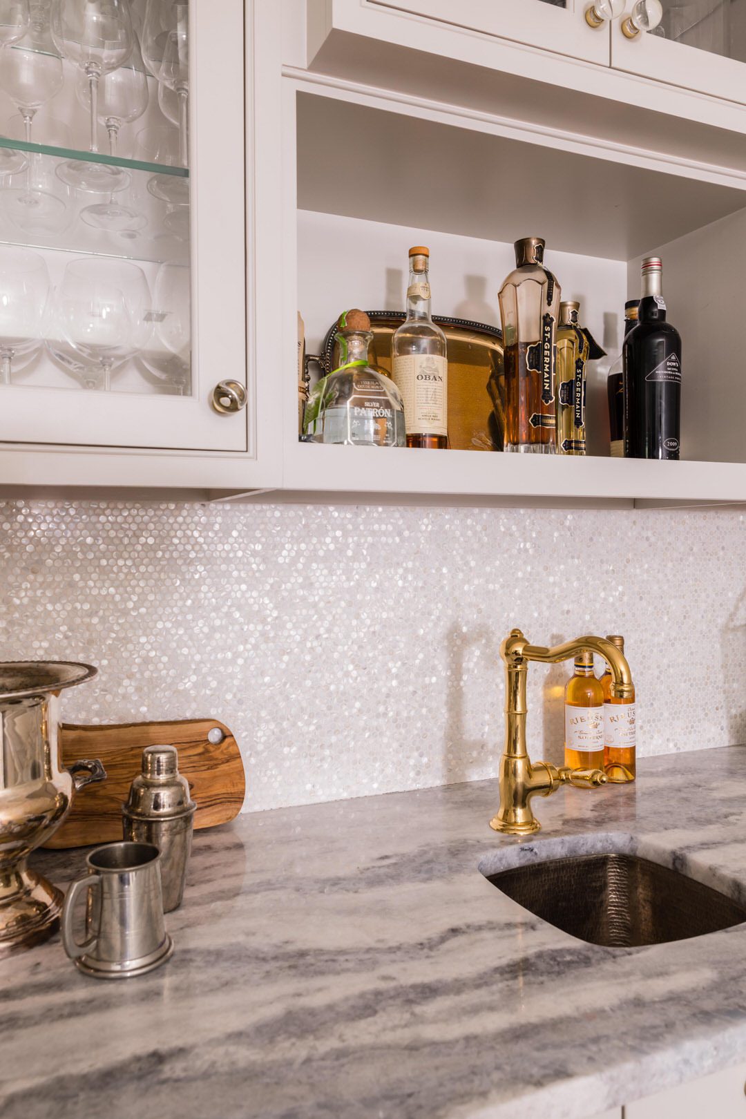 Mother of pearl backsplash with gold faucet in a home bar area