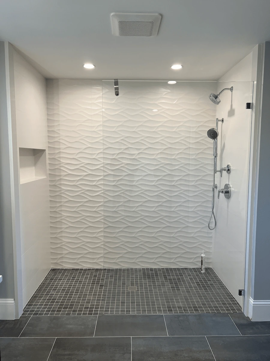 Modern curbless shower with textured white tiles and sleek fixtures