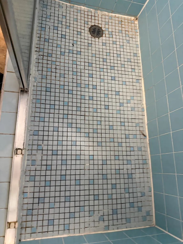 Cracked Mosaic Shower Floor With Loose Tile And Worn Grout
