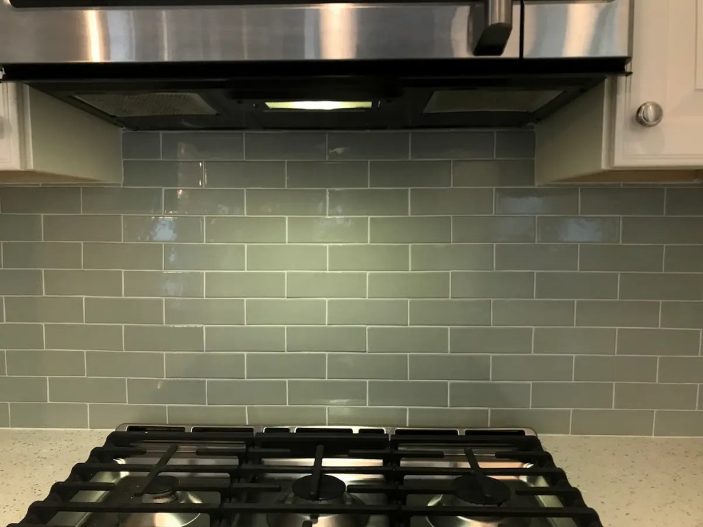 close view of handmade subway tile backsplash in Georgetown MA behind the range, tight joints with white grout and no brown edges showing
