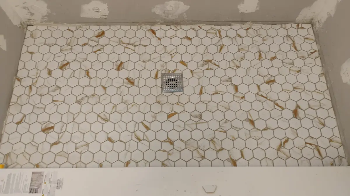 Hex tile shower floor installation with centered drain, before grouting