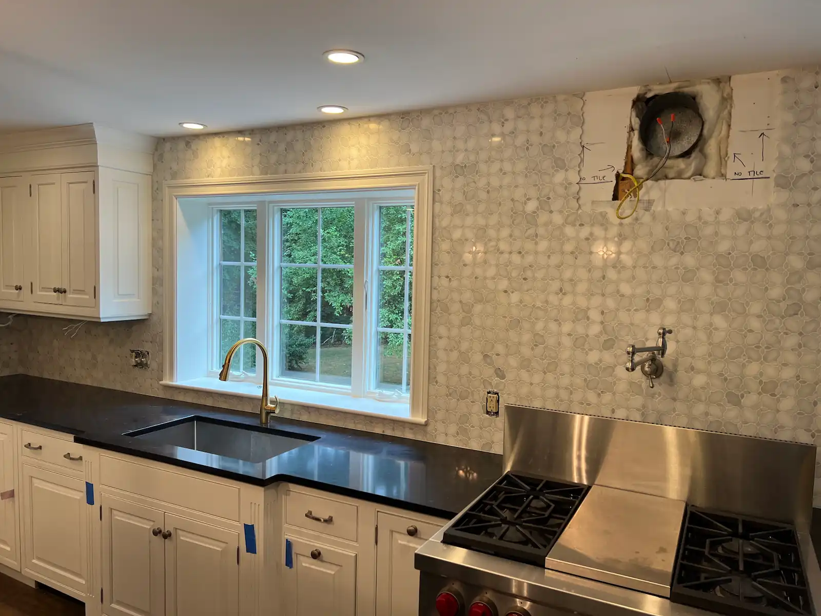 Backsplash tile installation in progress in Needham, MA kitchen — Jerusalem Heights Lotus marble mosaic with white cabinets and dark countertop