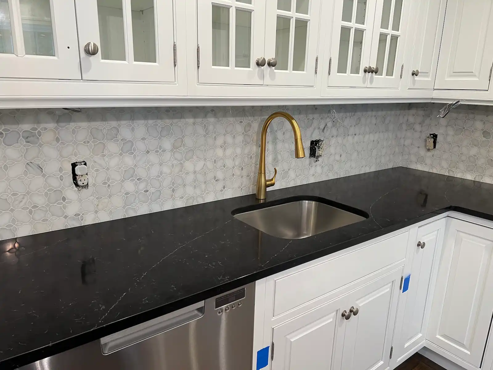 Backsplash tile installation in Needham, MA — Lotus marble mosaic around sink area with brass faucet and dark countertop