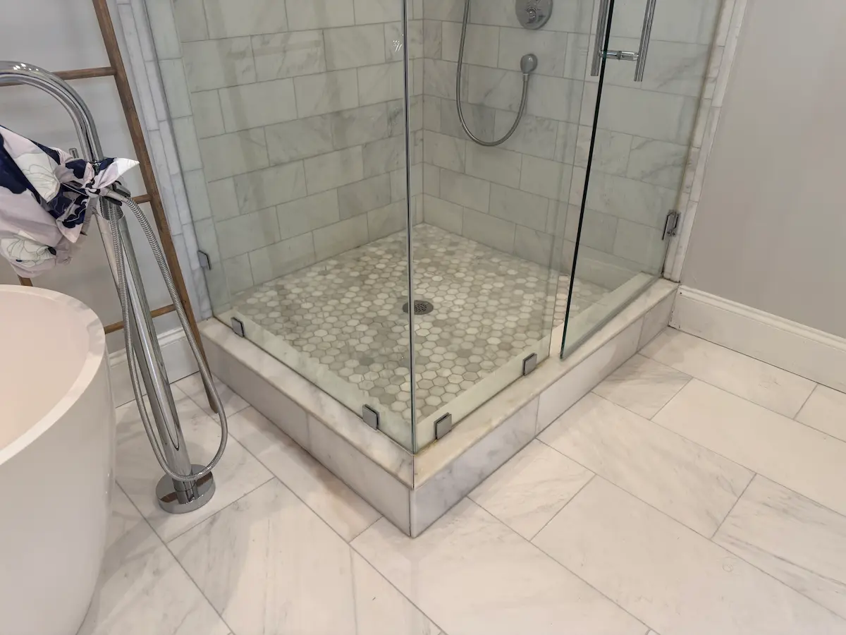 Failed marble shower installation in a Boston-area home — cracked grout, brown staining, and water damage caused by unqualified tile installer