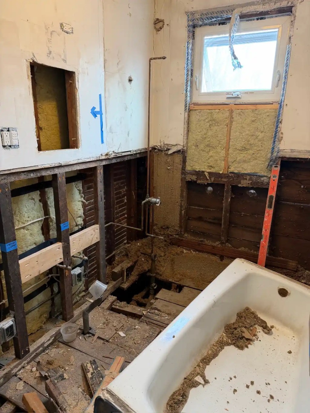 Somerville bathroom during demolition with the old cast-iron tub removed and walls opened up