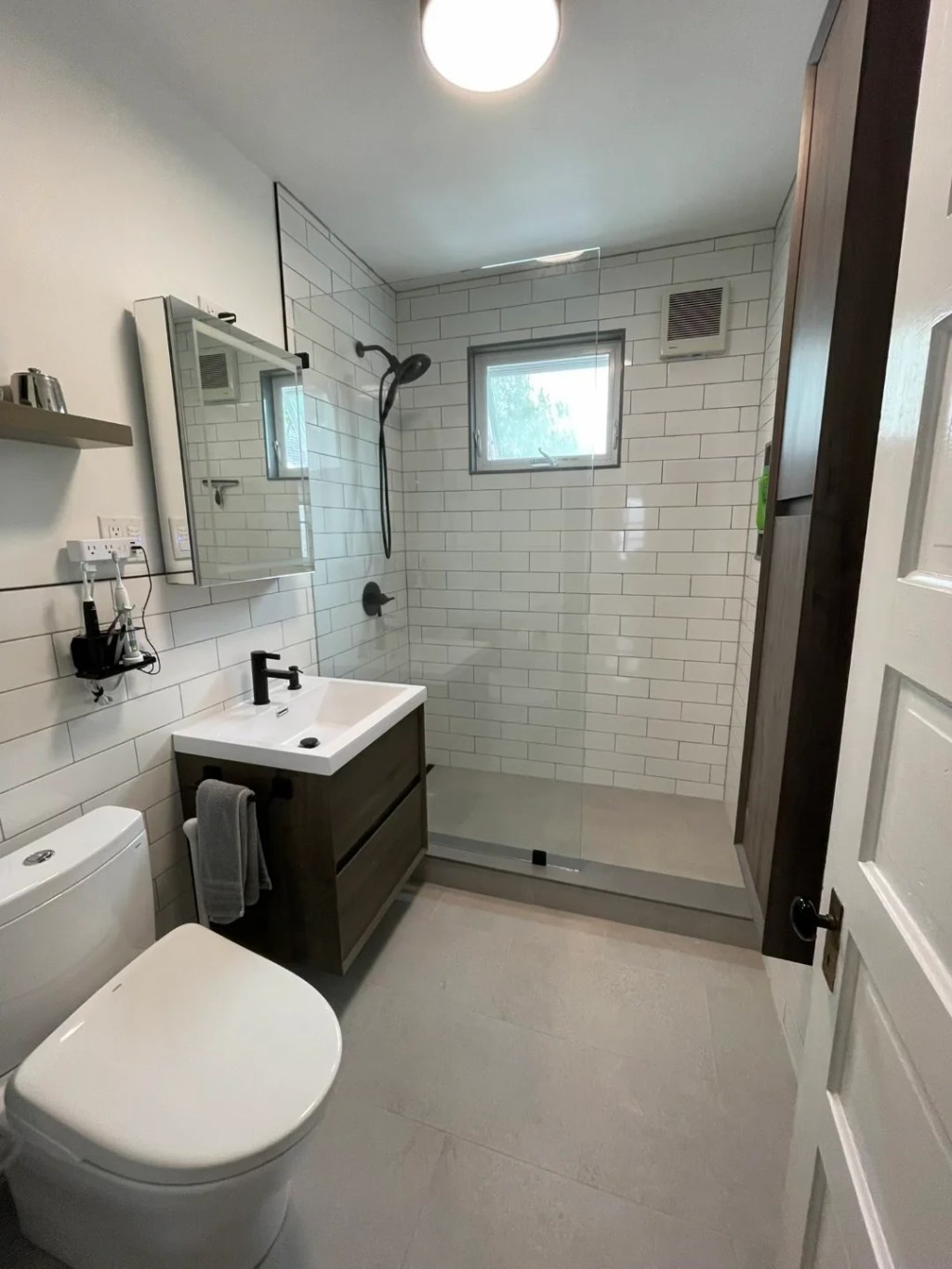 Finished tub-to-shower conversion in Somerville with white subway tile, walk-in glass shower, and floating vanity